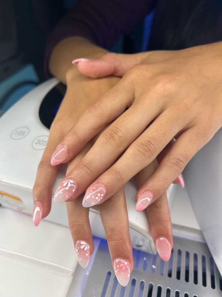 Almond nails in soft pink ombré with white floral accents
