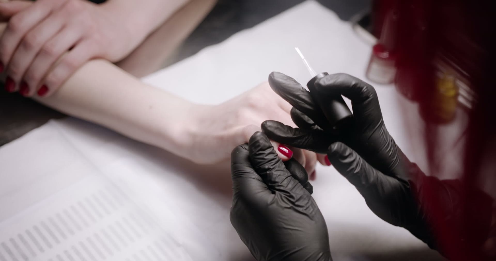 A nail technician painting a client’s nails at the studio