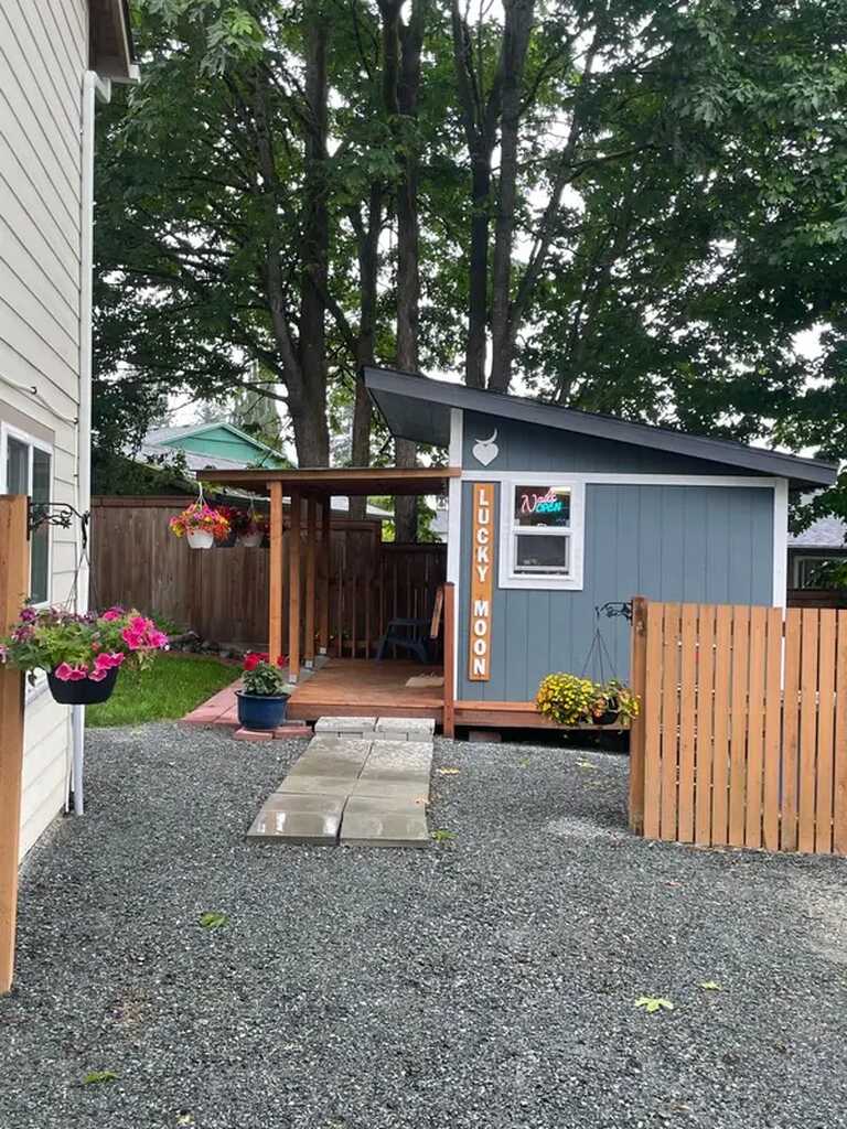 The slate-blue backyard studio with hanging flowers and a Lucky Moon sign